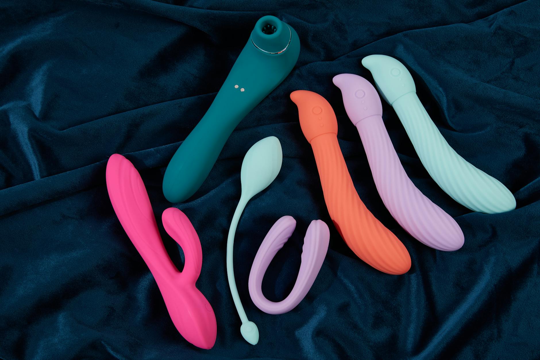 Woman holding blue and pink clitoral vibrators in a contemplative moment