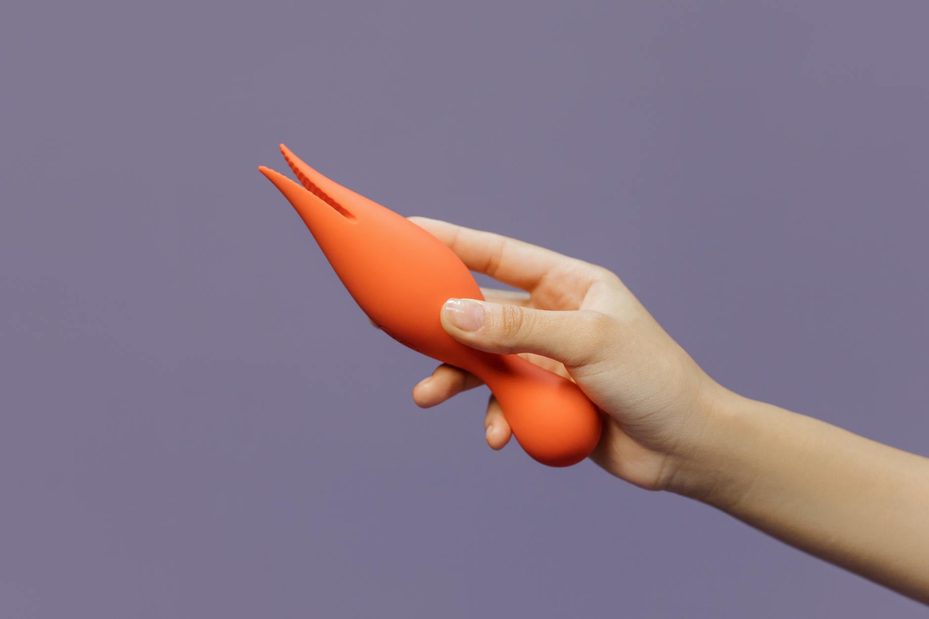 A hand holding a lemon vibrator against a minimalistic backdrop, showcasing modern sensuality and intimate care.