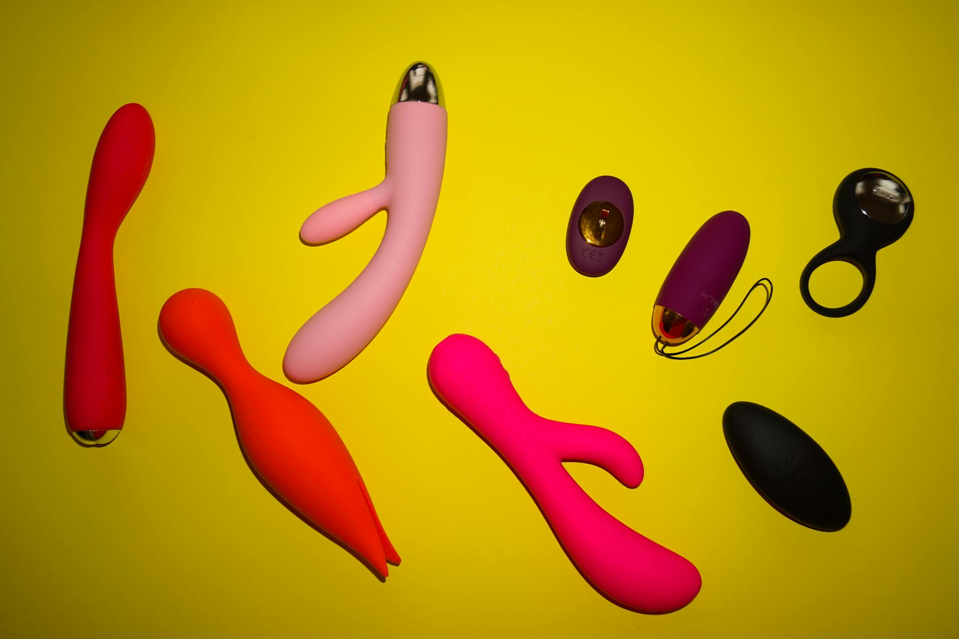 A vibrant flat lay of colorful adult toys and yellow elements on a bright surface