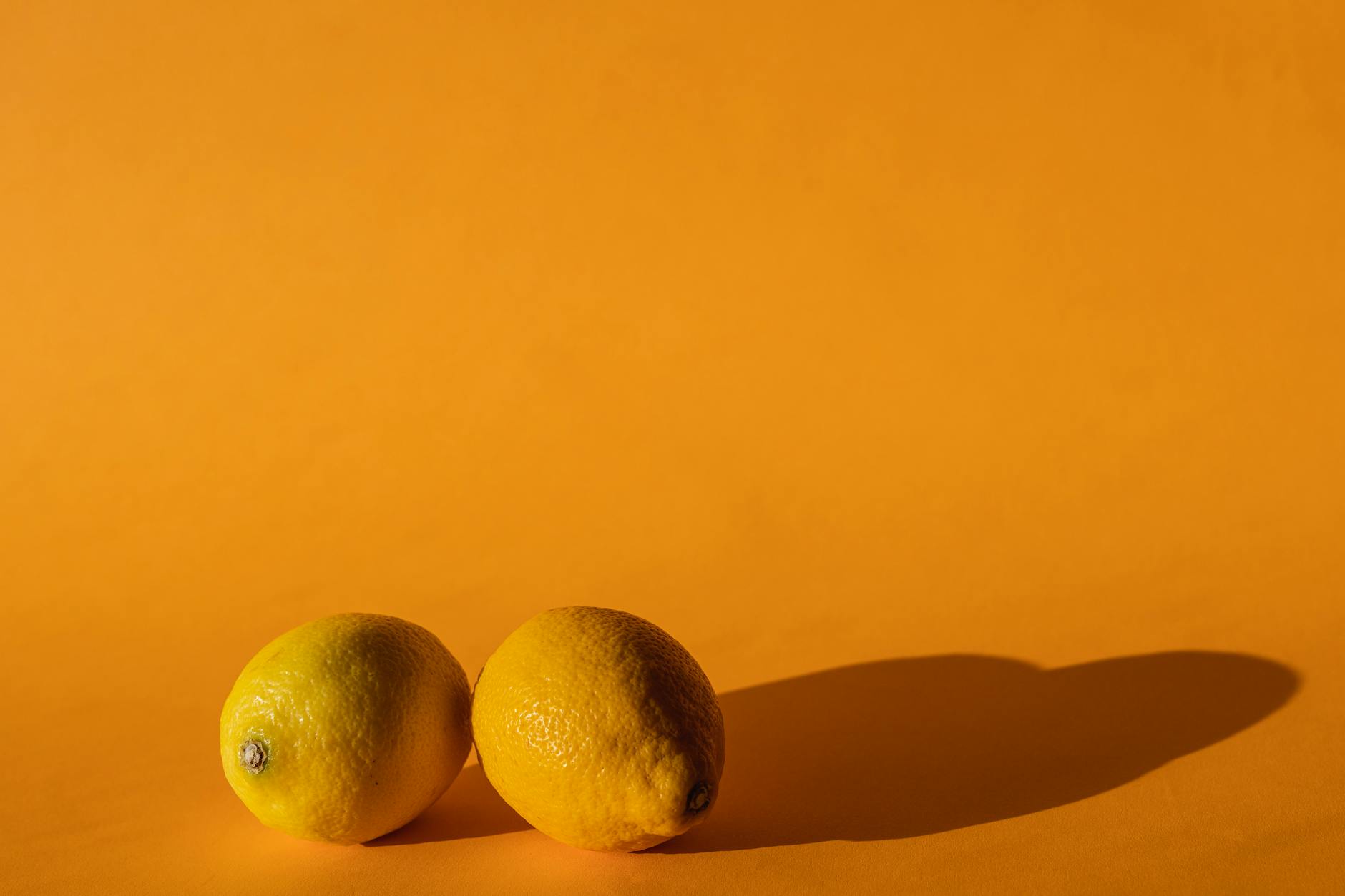 Ripe lemons on a bright yellow background, symbolizing the lemon clitoral vibrator
